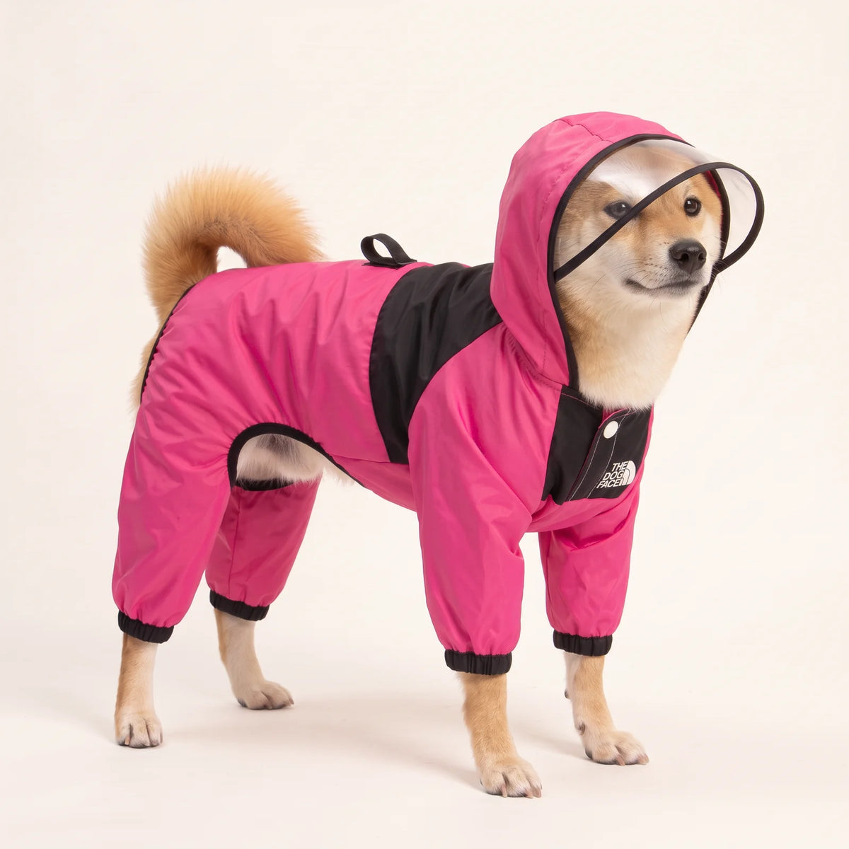 PuddlePup pink four-leg dog rain jacket with clear visor, shown on a Shiba Inu